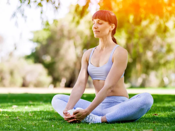 Giovane donna che pratica yoga nel parco — Foto Stock