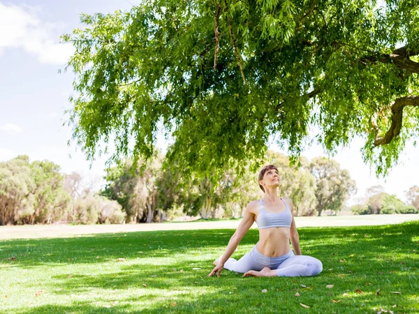 Ung kvinna utövar yoga i parken — Stockfoto