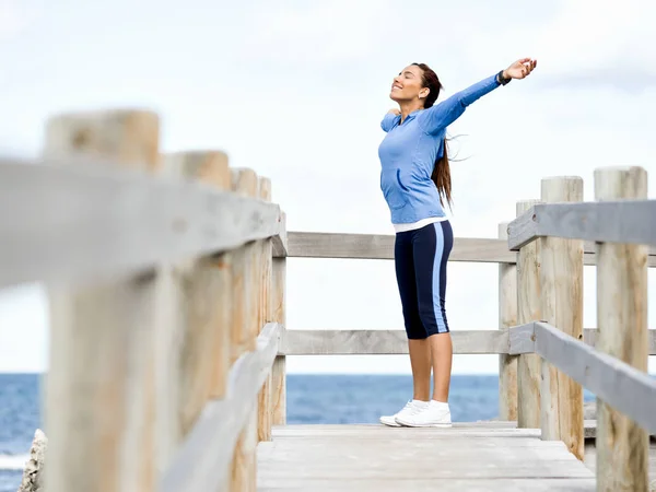 Атлетичная женщина в спортивной одежде стоит на берегу моря — стоковое фото