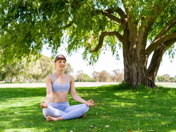 Genç kadın parkta yoga yapıyor. — Stok fotoğraf