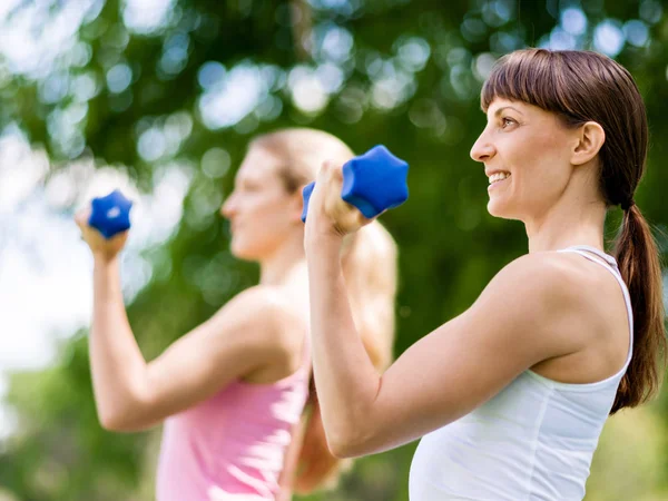Portrait of cheerful women in fitness wear exercising with dumbbell — Stock Photo, Image