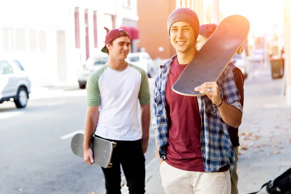 Adolescente menino andando na rua com seu skate — Fotografia de Stock