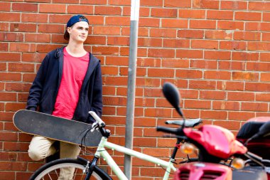 Duvarın yanında durduğunu kaykay ile genç çocuk