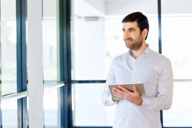 Genç yakışıklı işadamı onun touchpad ayakta kullanma office