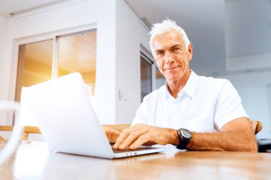 Adam evde dizüstü bilgisayarla çalışıyor.