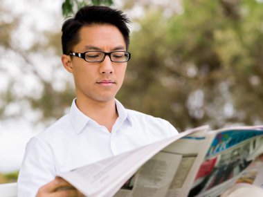 İş adamı parkta bir gazete okuyor