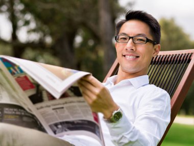 İş adamı parkta bir gazete okuyor