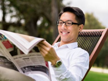 İş adamı parkta bir gazete okuyor