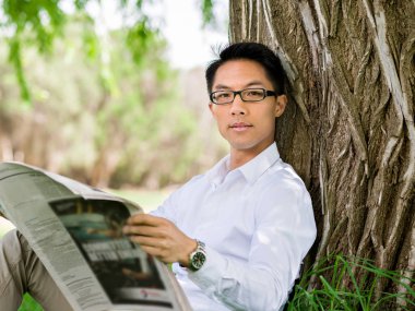 İş adamı parkta bir gazete okuyor