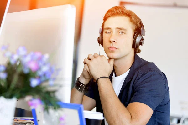 Junger Mann mit Kopfhörern im Büro — Stockfoto