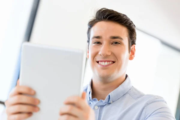 Junger gutaussehender Geschäftsmann sitzt mit seinem Touchpad im Büro — Stockfoto