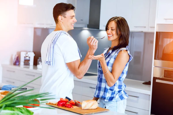 Jovem casal na cozinha degustação de alimentos — Fotografia de Stock