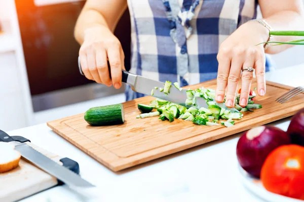 Vrouwelijke handen snijden komkommers — Stockfoto