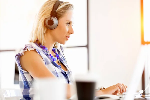 Mujer joven en la oficina con auriculares — Foto de Stock