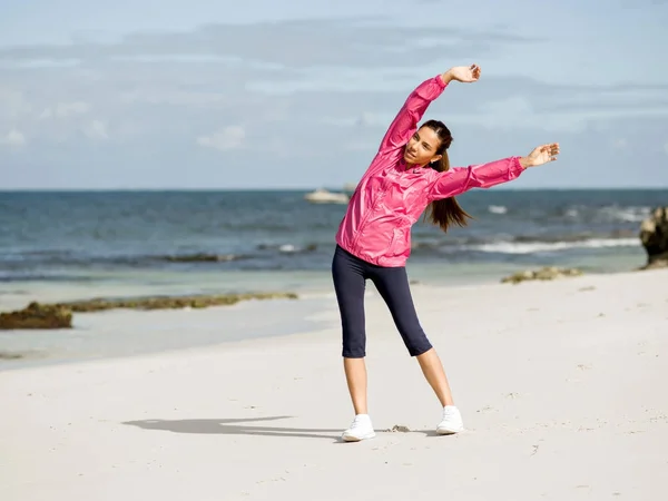 Jeune femme à la plage faire des exercices — Photo