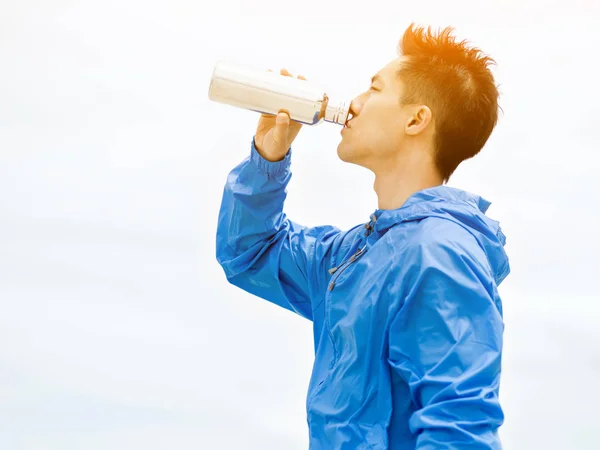 스포츠에서 젊은 남자 옷을 해변에서 운동 후 마시는 물 — 스톡 사진