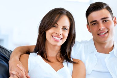 Genç çift evde otururken kameraya bakıyor