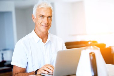 Adam evde dizüstü bilgisayarla çalışıyor.