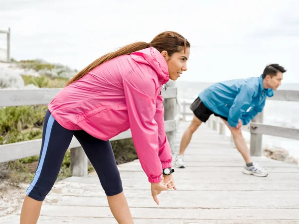 Jeune couple au bord de la mer faisant des exercices — Photo