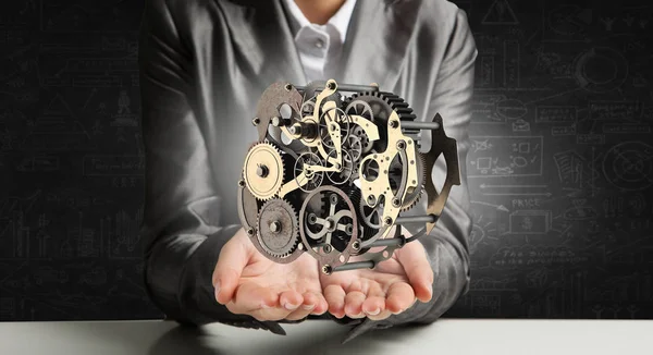 Cogwheel mechanism in hand. Mixed media — Stock Photo, Image