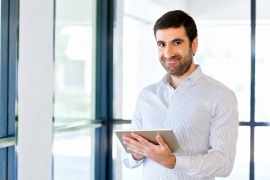 Genç yakışıklı işadamı onun touchpad ayakta kullanma office