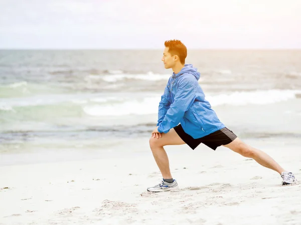 Молодой человек делает упражнения на пляже — стоковое фото