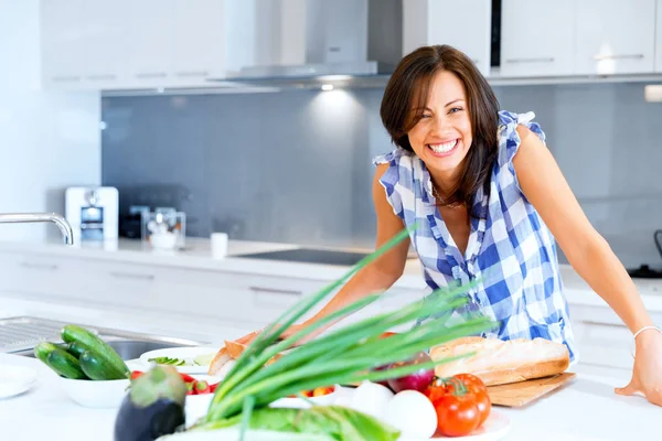 Hermosa mujer de pie en la cocina y sonriendo —  Fotos de Stock