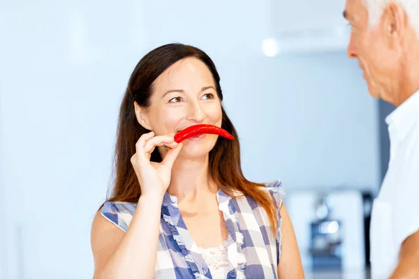 Mujer sosteniendo un pimiento rojo junto a su cara — Foto de Stock