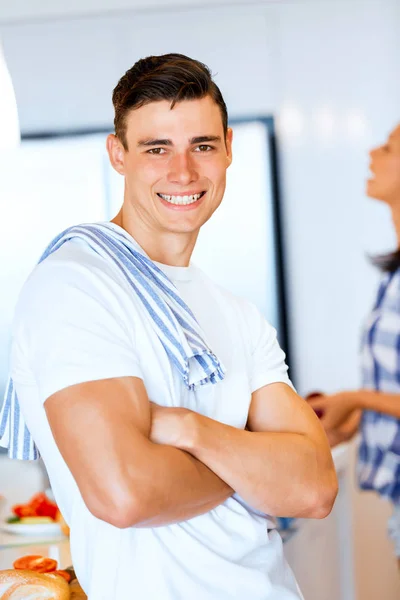 Young man standing in the kitchen and smiling — Stock Photo, Image