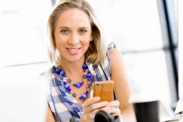 Zakenvrouw met mobiele telefoon in office — Stockfoto