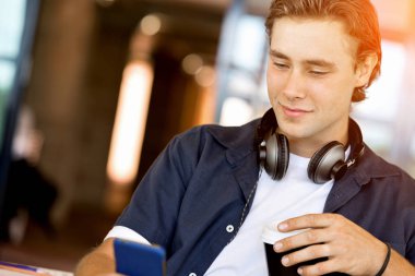 Kendine güvenen genç adam akıllı rahat kıyafet telefon tutarak