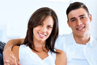 Genç çift evde otururken kameraya bakıyor