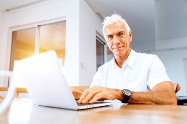 Adam evde dizüstü bilgisayarla çalışıyor.