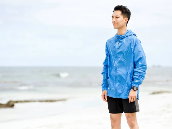 Jonge man staande op het strand — Stockfoto