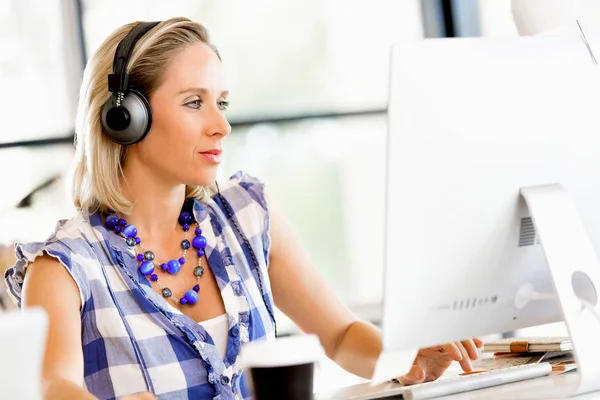 Mujer joven en la oficina con auriculares —  Fotos de Stock