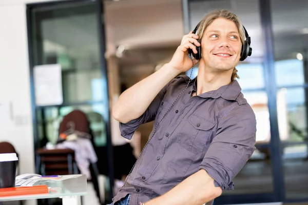 Jonge man in het kantoor met koptelefoon — Stockfoto