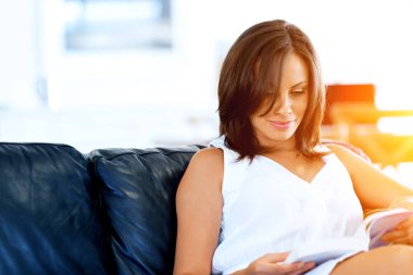 mutlu kadın kanepede oturan bir kitap okuma