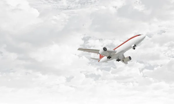 Airplane in cloudy sky . Mixed media — Stock Photo, Image