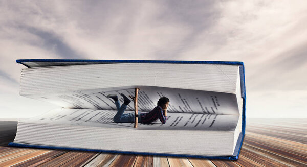 Young man lying among pages of big book. Mixed media