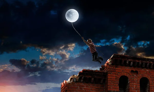 꼬마가 달을 잡고 있어. 혼합 매체 — 스톡 사진
