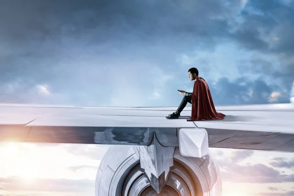 Молодий бізнесмен супер герой на краю крила літака — стокове фото