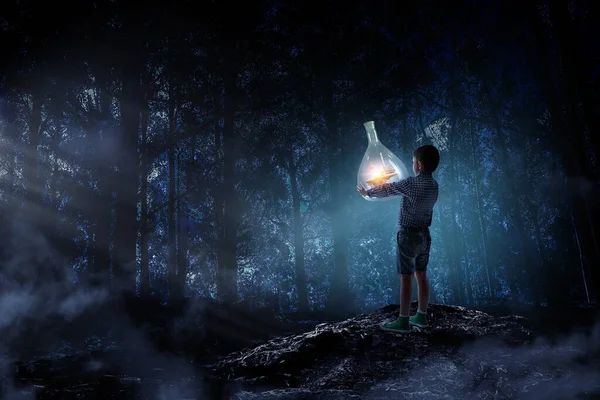 Мальчик держит стеклянную фляжку с пейзажем внутри — стоковое фото