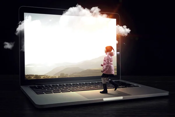 Bambina cammina verso il computer portatile enorme — Foto Stock
