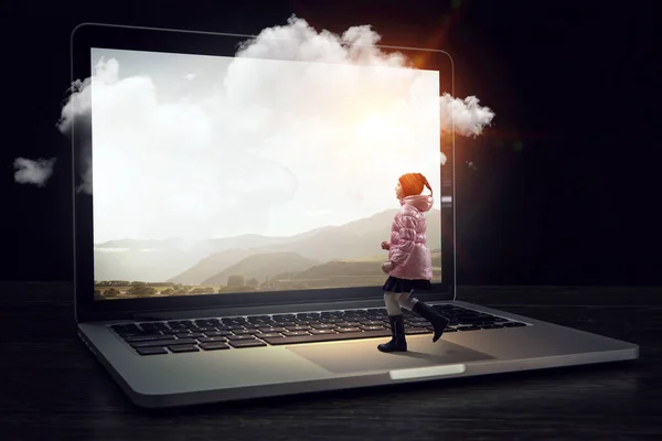 Petite fille marche vers un énorme ordinateur portable — Photo