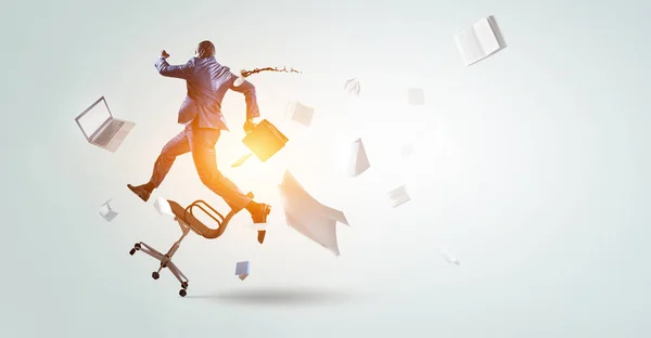 Back view of running black businessman with briefcase and falling around office objects — Stock Photo, Image