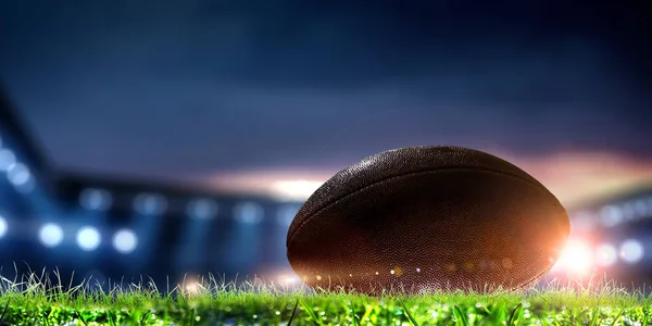 Arena de futebol noturno em luzes com uma bola de perto — Fotografia de Stock