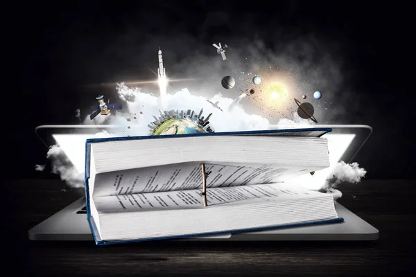 Ноутбук с книгой, планетой и космосом на темном фоне — стоковое фото