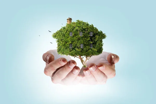 Χέρι που κρατάει πράσινο σπίτι. Μεικτά μέσα — Φωτογραφία Αρχείου