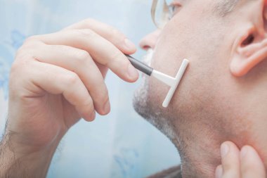 Gülümseyen adam sakalını tek kullanımlık ustura ile tıraş