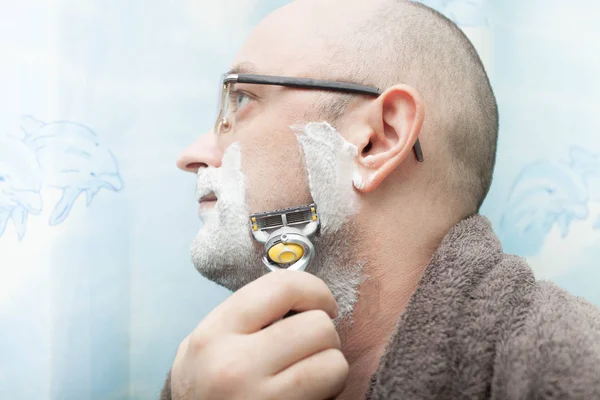 Homem sério barbeando sua barba por lâmina de barbear — Fotografia de Stock